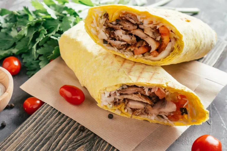 Chicken shawarma wrap sliced in half with cabbage and tomato on flatbread with fresh parsley