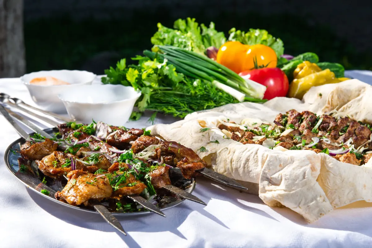 Grilled meat skewers with herbs and onion, served with lavash and fresh vegetables