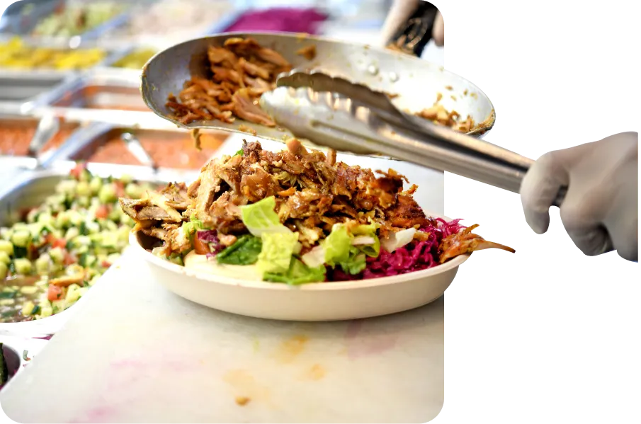 Chicken shawarma bowl with fresh salad, red cabbage and hummus being topped with tongs