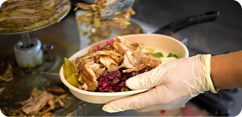 Freshly carved chicken shawarma bowl with red cabbage and pickles served by the rotisserie