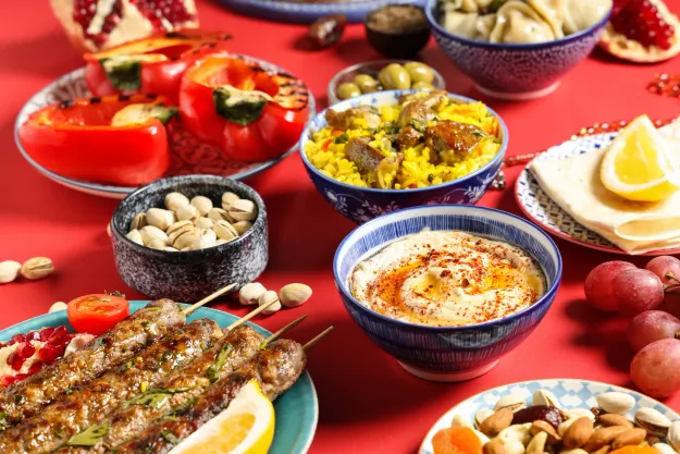 Middle Eastern spread with kofta skewers, hummus, saffron rice, stuffed peppers, and nuts