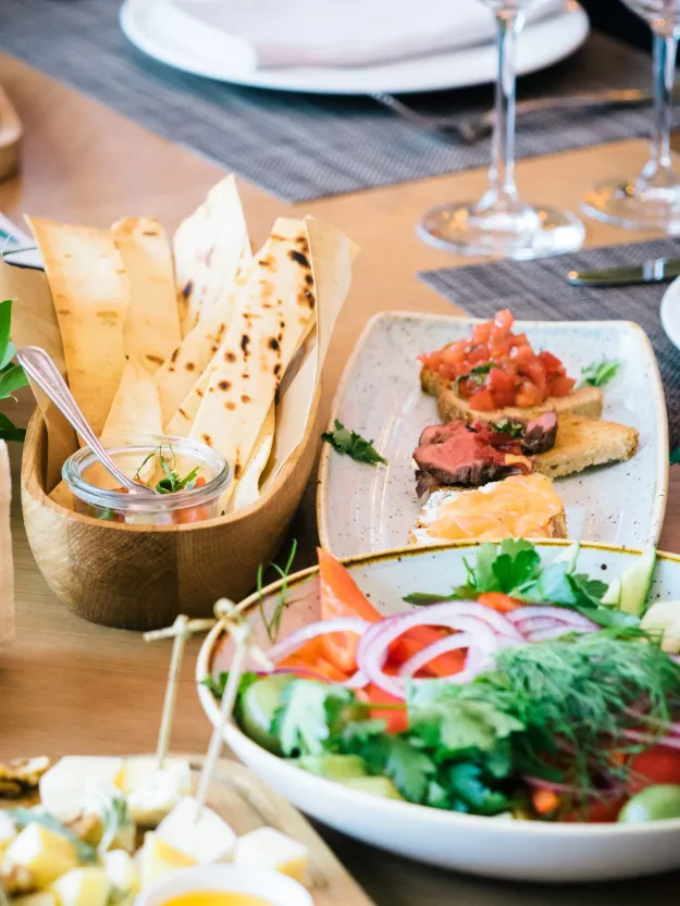 Set table with flatbread, bruschetta, fresh salad, and mezze plates alongside wine glasses
