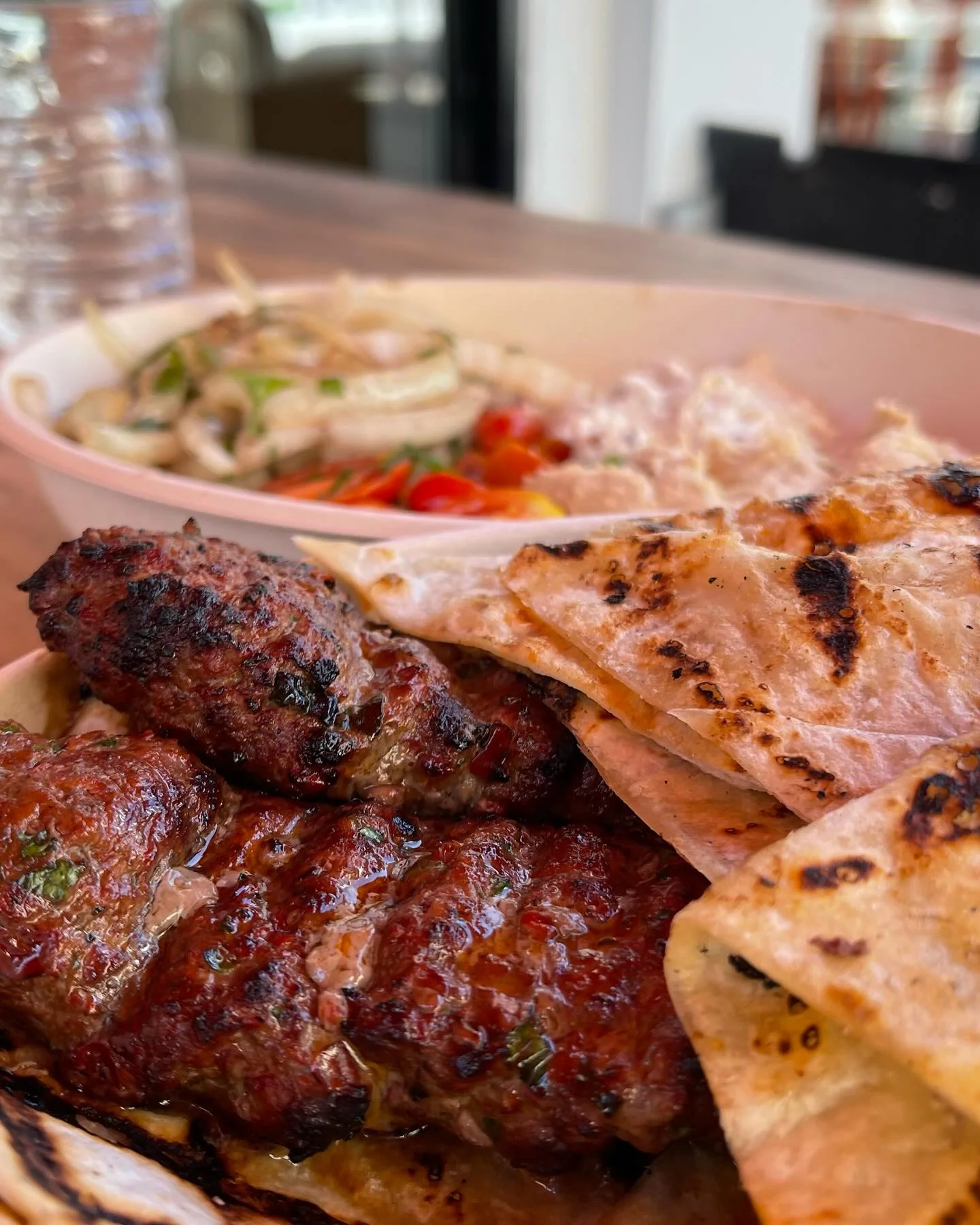 Grilled kofta kebabs with charred flatbread and a side of onion salad