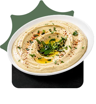 Bowl of hummus topped with olive oil, parsley, and paprika